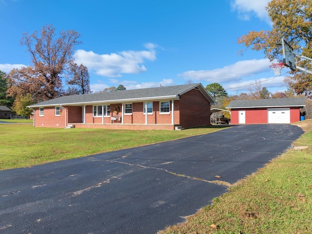 ranch-style house featuring an outbuilding, a porch, a garage, and a front lawn