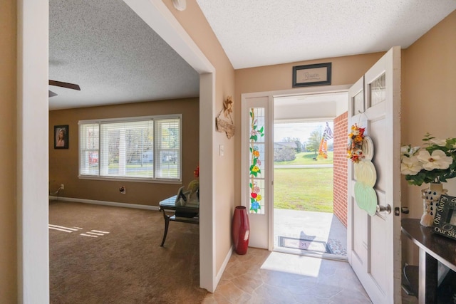 foyer with light carpet, ceiling fan, and a textured ceiling