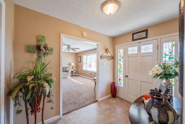 carpeted entrance foyer with ceiling fan and a textured ceiling