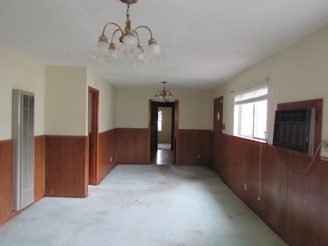 spare room with wood walls and a chandelier