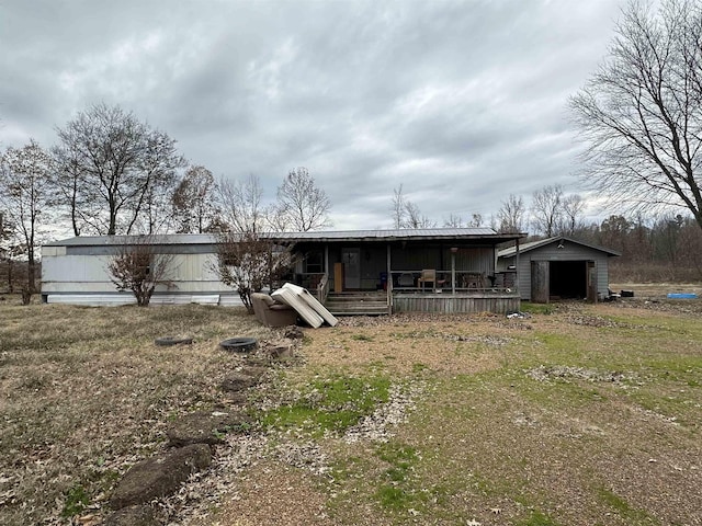 rear view of house with covered porch, an outdoor structure, and a garage