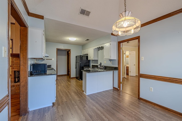 kitchen featuring white cabinets, a textured ceiling, light wood-type flooring, and black fridge