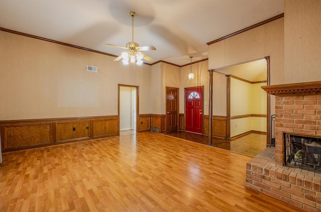 unfurnished living room with hardwood / wood-style flooring, ceiling fan, ornamental molding, and a brick fireplace