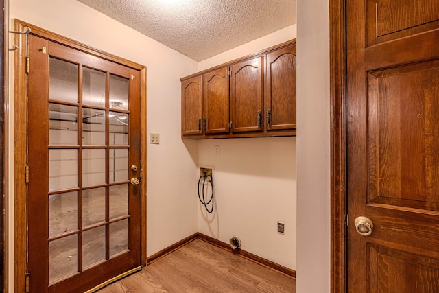 washroom featuring cabinets, light hardwood / wood-style flooring, washer hookup, a textured ceiling, and hookup for an electric dryer