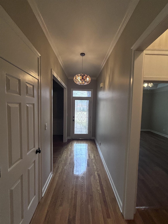 entryway with a chandelier, dark wood-type flooring, and ornamental molding