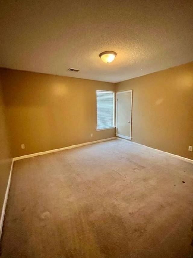 carpeted spare room with a textured ceiling