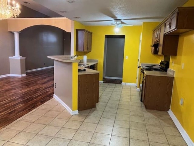 kitchen with gas range gas stove, sink, lofted ceiling, ceiling fan with notable chandelier, and light wood-type flooring