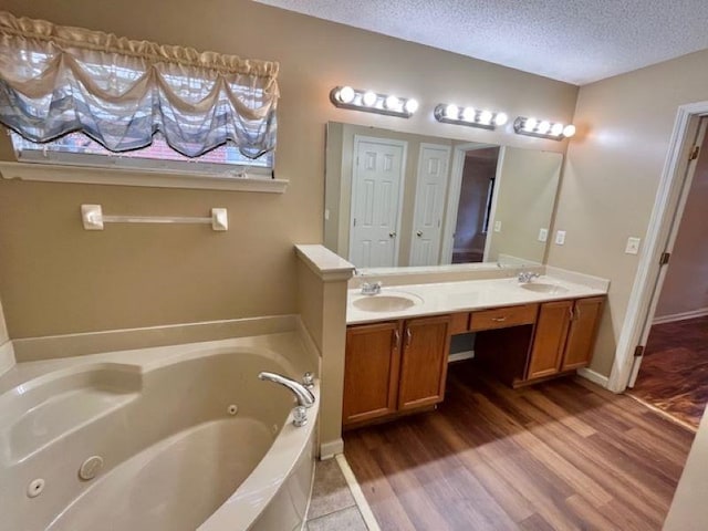 bathroom with a bathing tub, vanity, wood-type flooring, and a textured ceiling