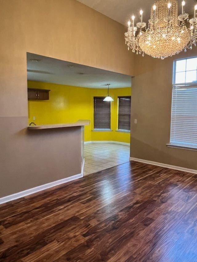 empty room with dark hardwood / wood-style flooring and an inviting chandelier