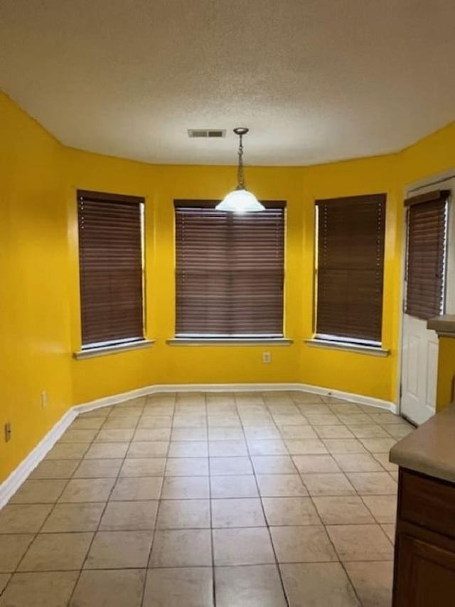 unfurnished dining area featuring light tile patterned floors and a textured ceiling