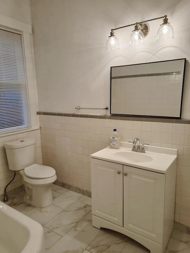 bathroom featuring vanity, tile walls, and toilet