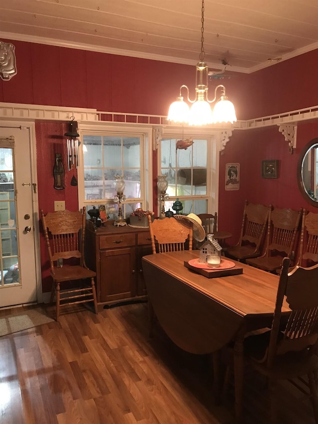 dining space with wood-type flooring, crown molding, a wealth of natural light, and a chandelier