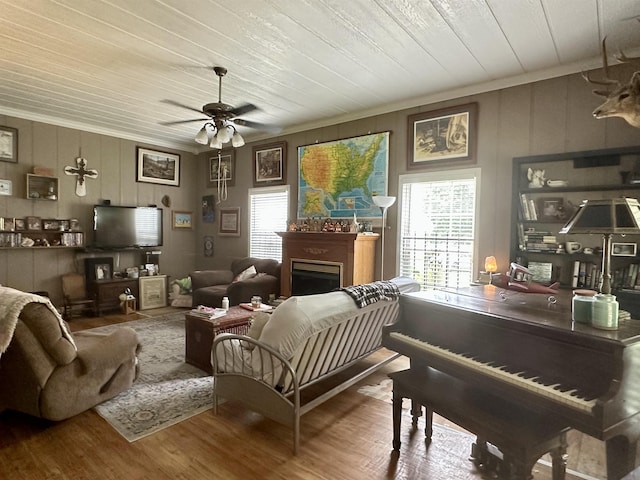 living room with wood-type flooring, a wealth of natural light, crown molding, and ceiling fan