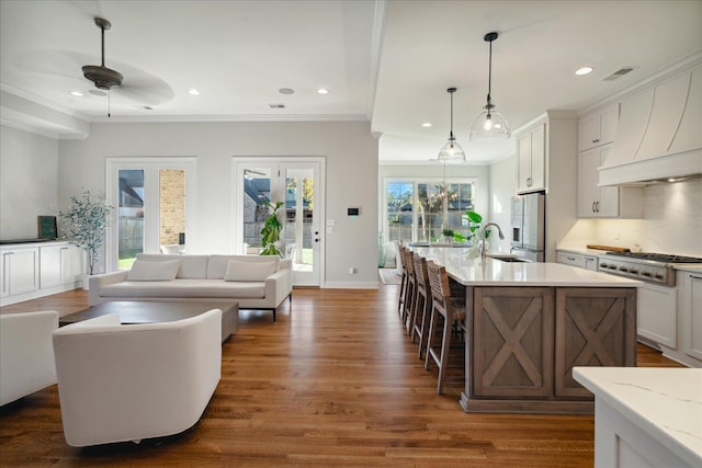 kitchen with white cabinets, dark hardwood / wood-style floors, stainless steel appliances, and a kitchen island with sink