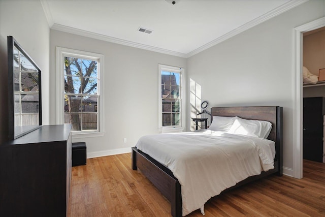 bedroom featuring multiple windows, crown molding, and wood-type flooring