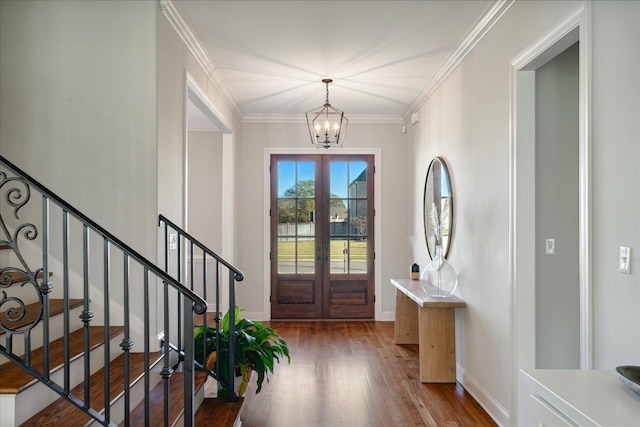 foyer entrance featuring french doors, dark hardwood / wood-style floors, crown molding, and a notable chandelier