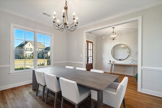 dining room featuring wood-type flooring, crown molding, and a notable chandelier