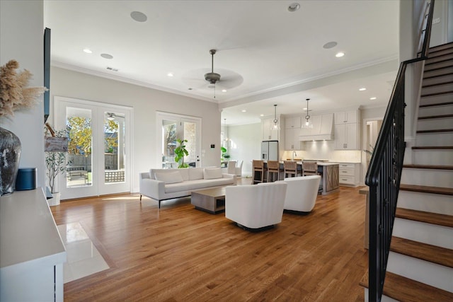 living room featuring hardwood / wood-style floors, ceiling fan, ornamental molding, and sink