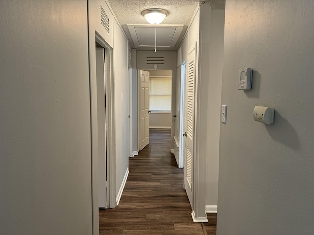 hall with a textured ceiling and dark wood-type flooring