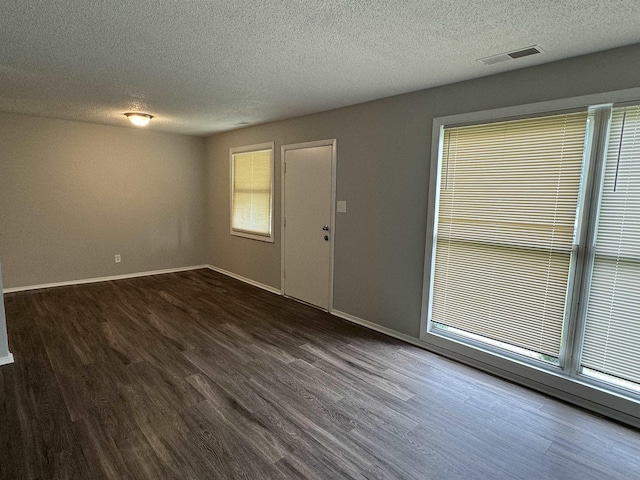 unfurnished room with a textured ceiling and dark hardwood / wood-style floors