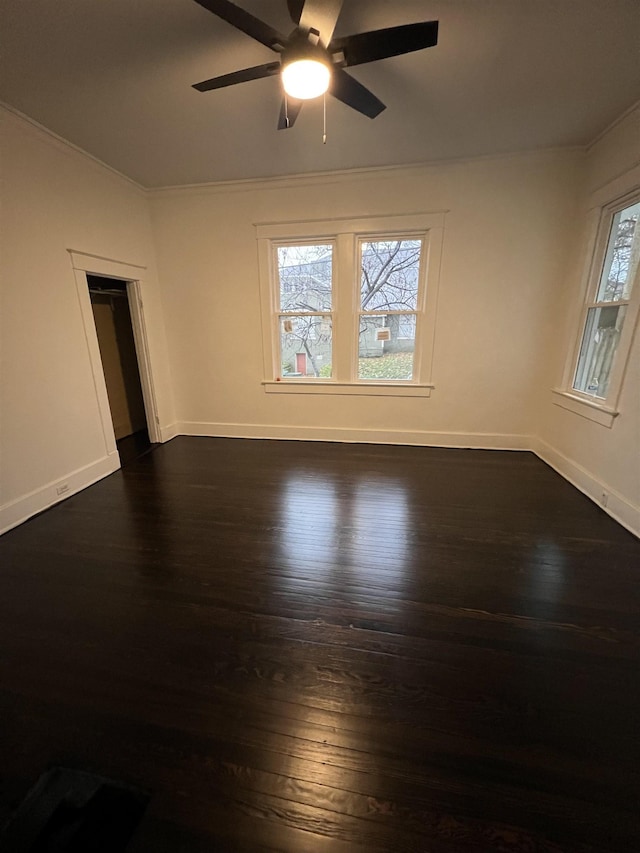 unfurnished room with a healthy amount of sunlight, ceiling fan, crown molding, and dark wood-type flooring