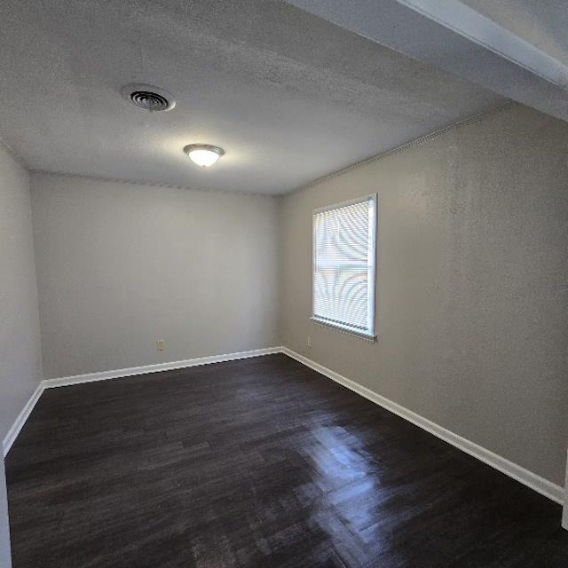 empty room with a textured ceiling and dark hardwood / wood-style flooring