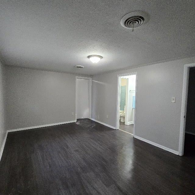 empty room with dark hardwood / wood-style flooring and a textured ceiling