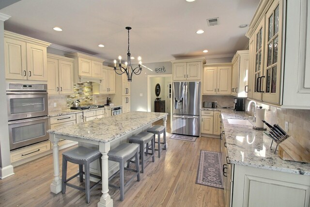 kitchen featuring a kitchen island, light stone countertops, sink, and appliances with stainless steel finishes