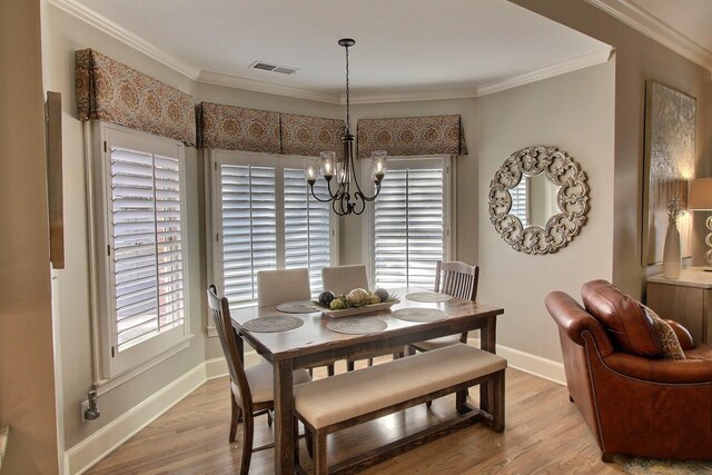 dining area with an inviting chandelier, light hardwood / wood-style flooring, plenty of natural light, and ornamental molding