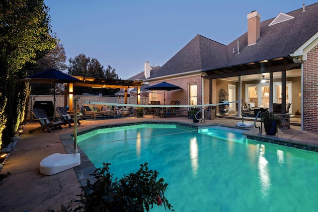 pool at dusk with a patio and ceiling fan