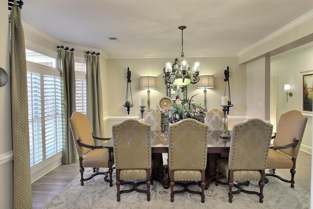 dining space featuring light wood-type flooring, ornamental molding, and a chandelier