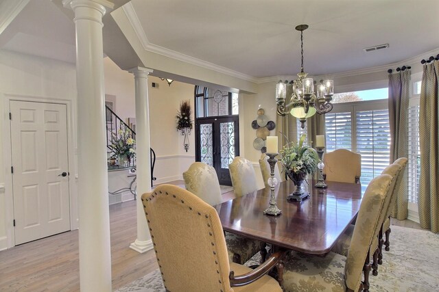 dining room with a chandelier, light hardwood / wood-style flooring, ornamental molding, and ornate columns