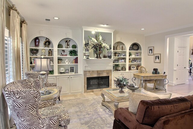 living room featuring built in shelves, a tiled fireplace, and ornamental molding