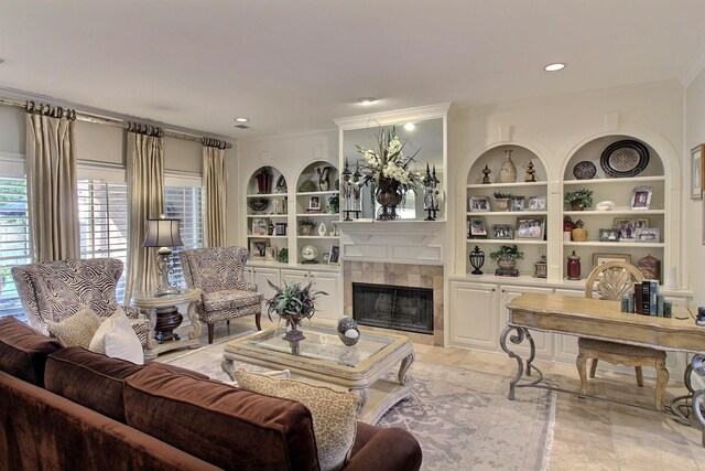 living room featuring built in features, ornamental molding, and a tiled fireplace