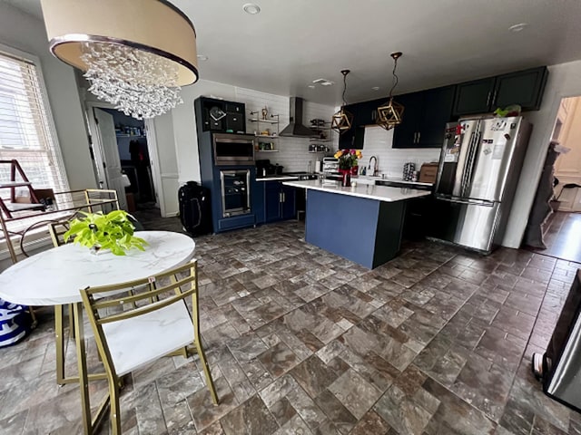 kitchen with wall chimney exhaust hood, pendant lighting, decorative backsplash, a kitchen island, and appliances with stainless steel finishes