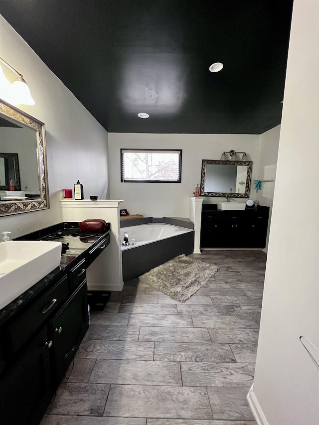 bathroom with a tub, vanity, and wood-type flooring