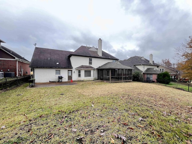 rear view of property featuring a sunroom, central AC unit, a patio area, and a lawn