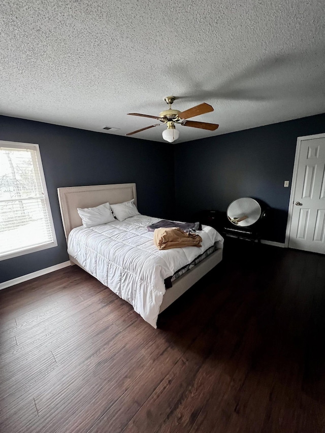 bedroom featuring a textured ceiling, ceiling fan, and dark wood-type flooring