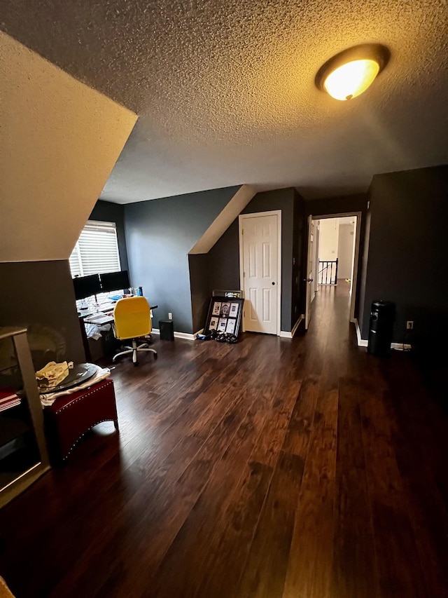 additional living space featuring a textured ceiling, dark hardwood / wood-style flooring, and lofted ceiling