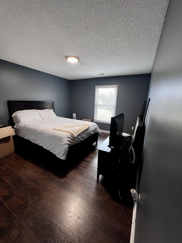 bedroom featuring a textured ceiling and dark wood-type flooring