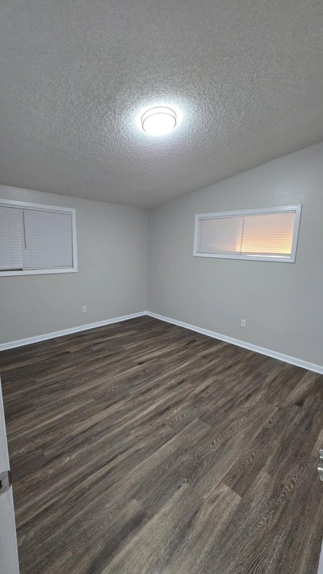 empty room featuring a textured ceiling and dark wood-type flooring