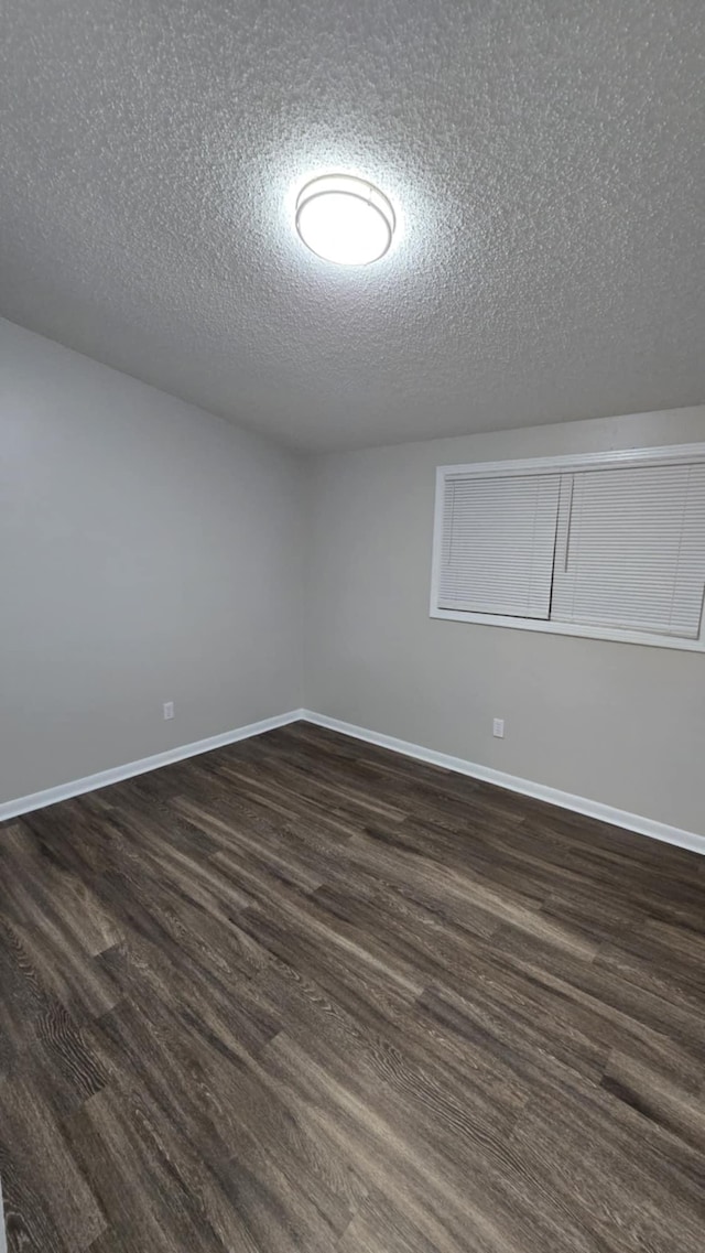 additional living space featuring a textured ceiling and dark wood-type flooring