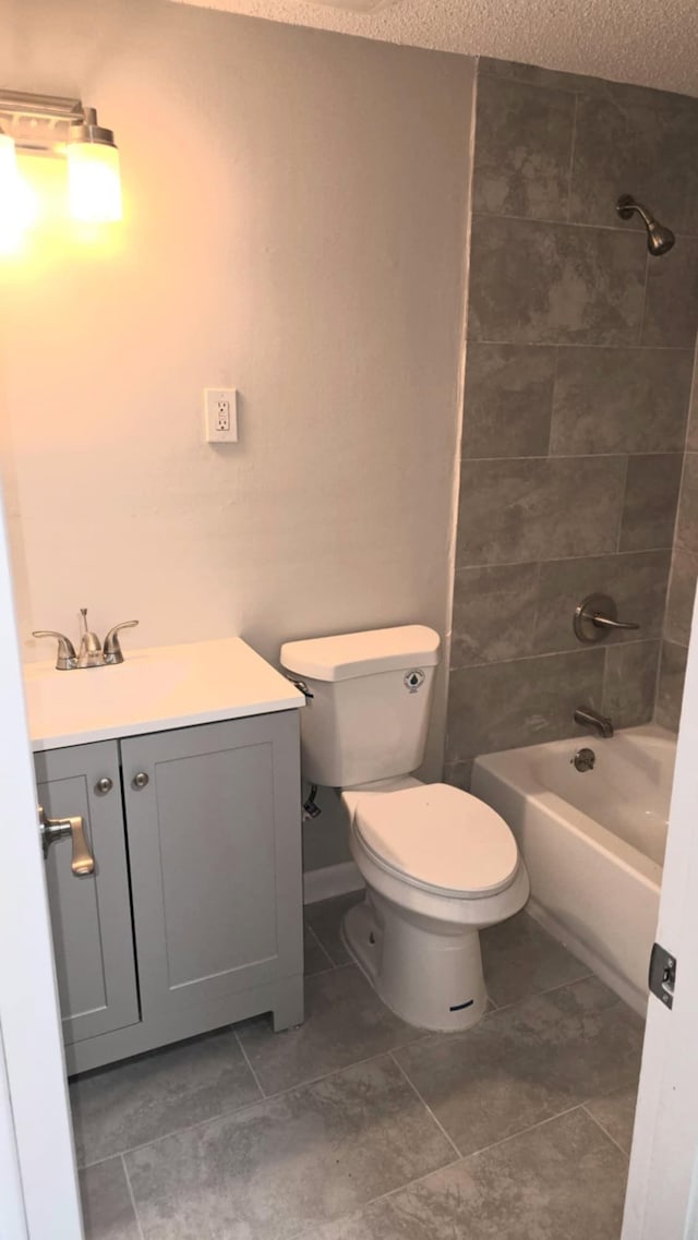 full bathroom featuring vanity, tiled shower / bath, a textured ceiling, and toilet