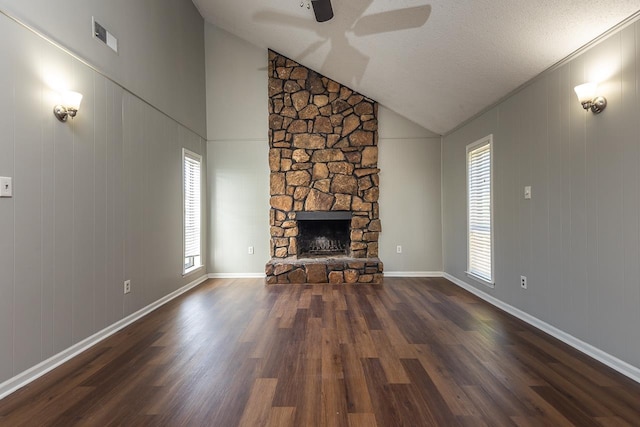 unfurnished living room featuring high vaulted ceiling, a stone fireplace, ceiling fan, a textured ceiling, and dark hardwood / wood-style flooring