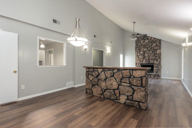 interior space with ceiling fan, a stone fireplace, dark wood-type flooring, and high vaulted ceiling