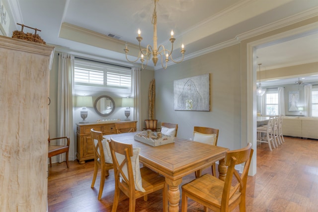 dining space with hardwood / wood-style flooring, an inviting chandelier, crown molding, and a tray ceiling