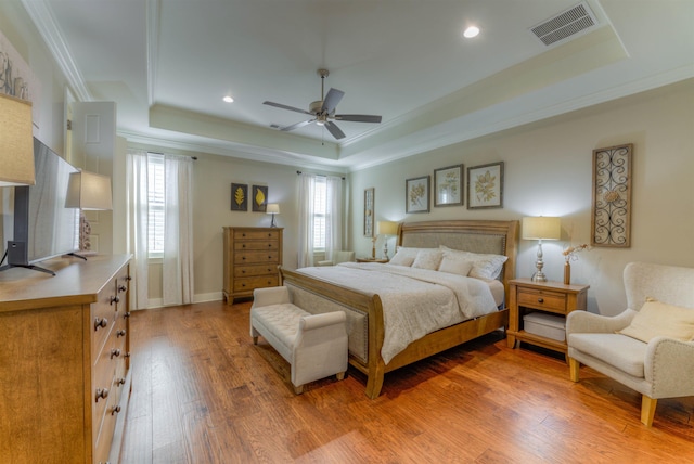 bedroom with a tray ceiling, crown molding, ceiling fan, and hardwood / wood-style flooring