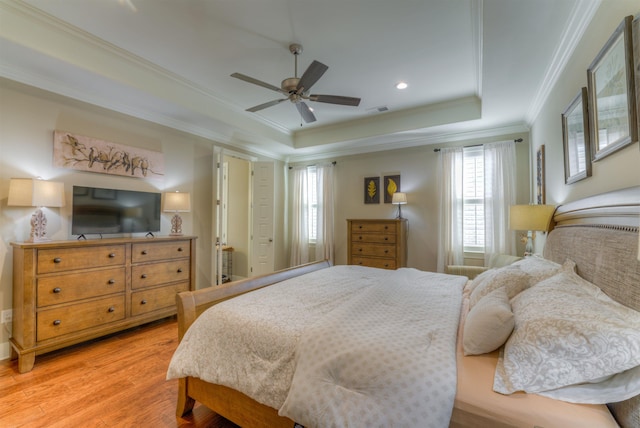 bedroom featuring ceiling fan, wood-type flooring, crown molding, and a tray ceiling