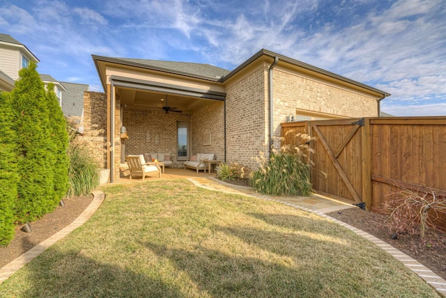 rear view of house with outdoor lounge area, ceiling fan, a patio, and a lawn