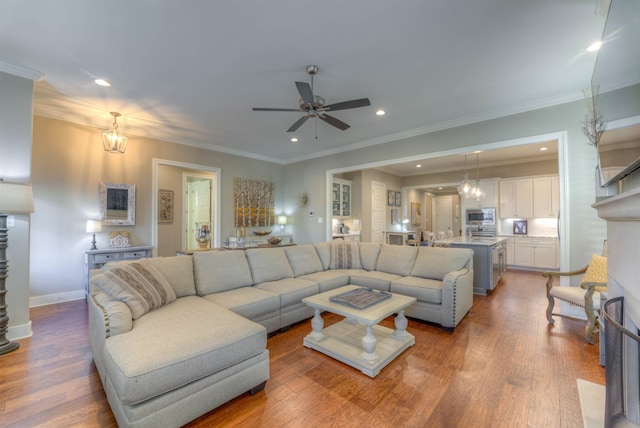 living room featuring ceiling fan, a fireplace, wood-type flooring, and crown molding